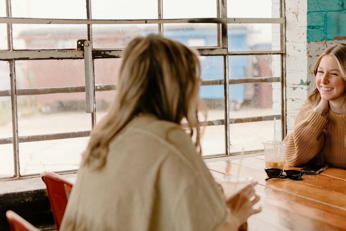 Two friends talking over coffee at a cafe table