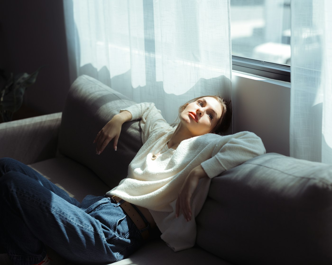 A woman sunk back into her sofa by the window, eyes closed