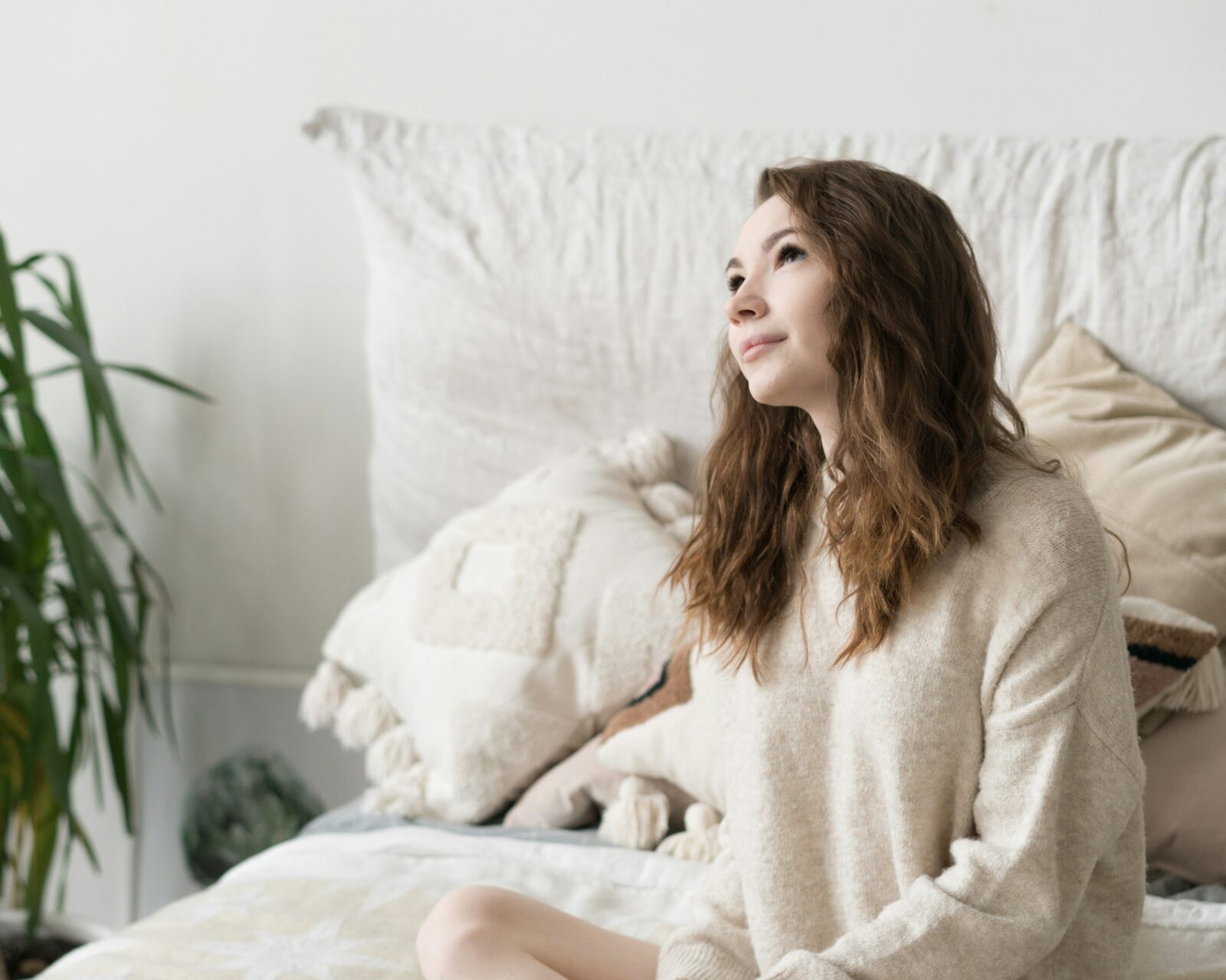 A woman sitting cross-legged on her bed, mid conversation