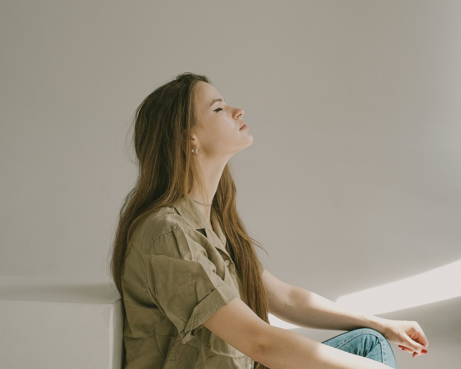 A woman leaning back into the sunlight, letting her shoulders drop