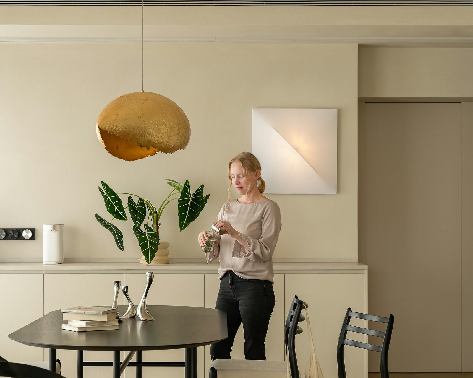 A woman stepping away from work with a drink in a sunlit kitchen